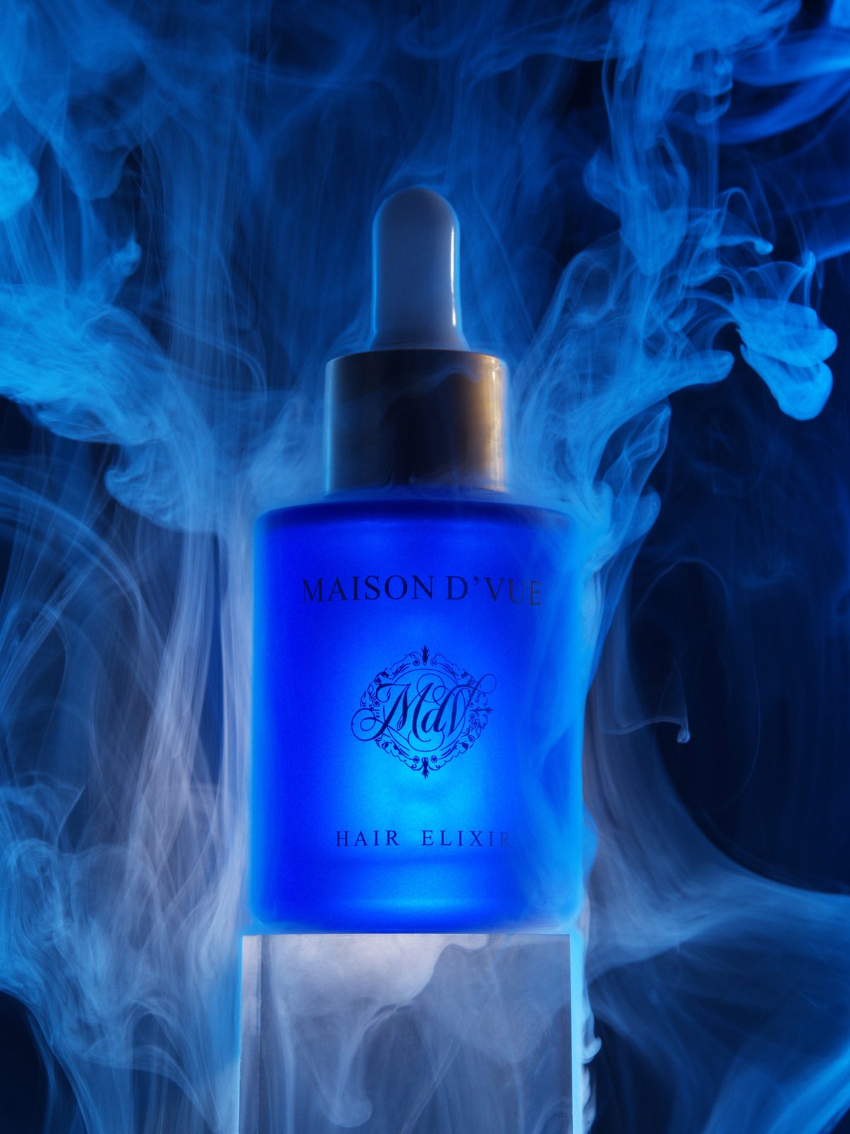 The Signature — 30ml MAISON D'VUE Hair Elixir lit cobalt, wreathed in blue smoke