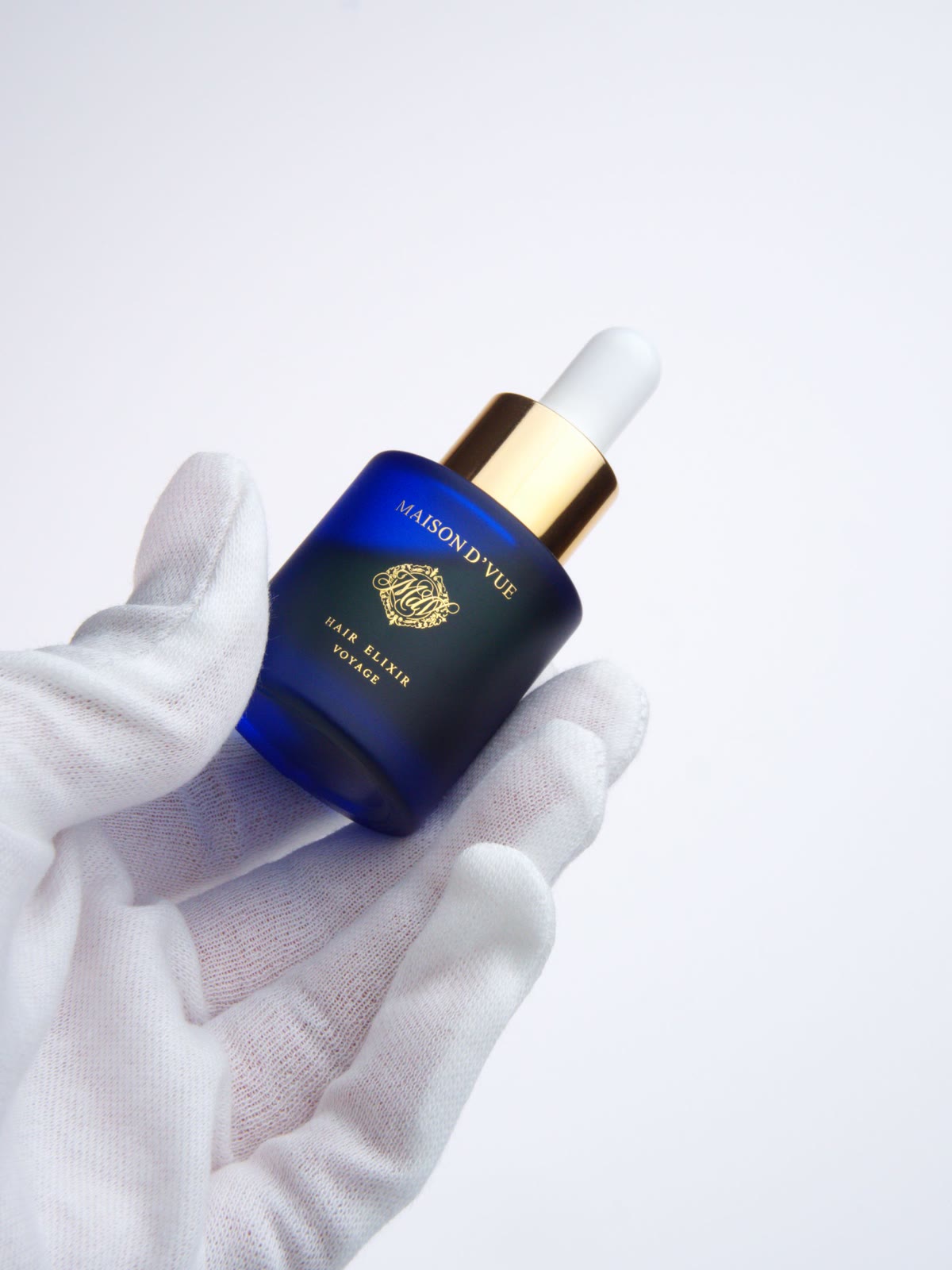 The Voyage — 10ml MAISON D'VUE Hair Elixir held in a white cotton glove