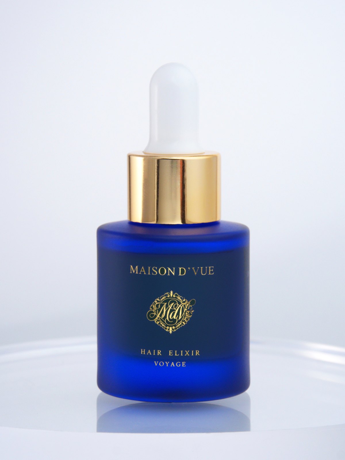 The Voyage — 10ml MAISON D'VUE Hair Elixir in cobalt frosted glass with gold cap, lit against white