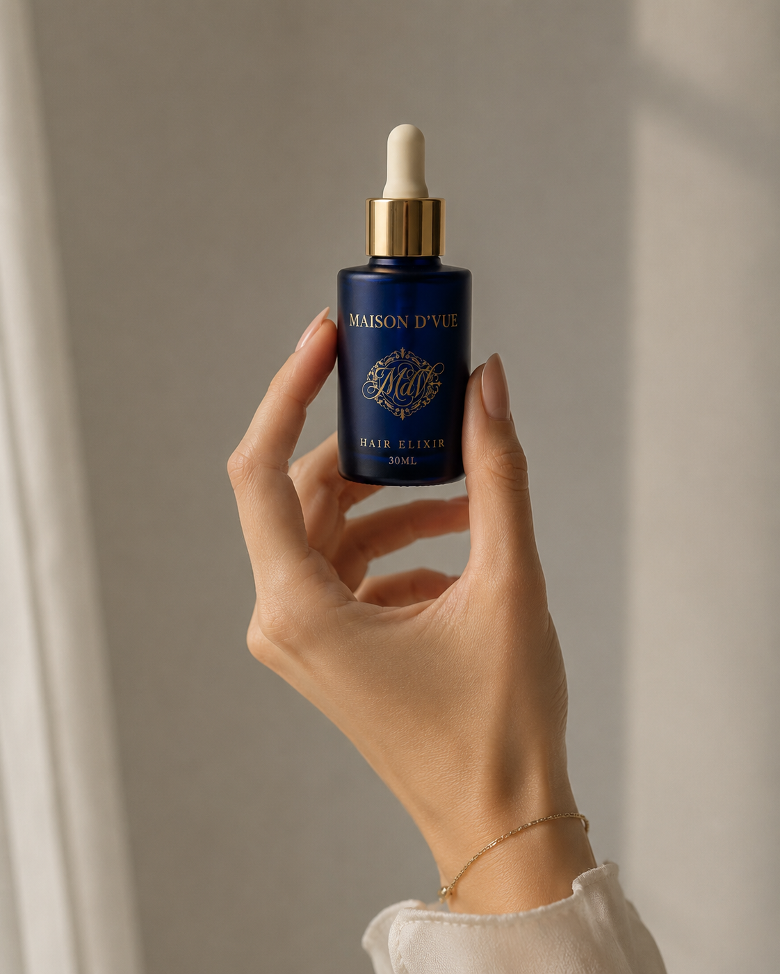 The Signature &mdash; 30ml MAISON D'VUE Hair Elixir in cobalt frosted glass with matte gold cap, held in hand