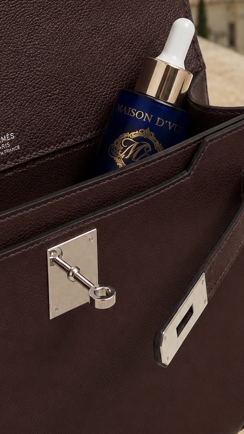 The Voyage tucked in the pocket of a Hermès leather bag